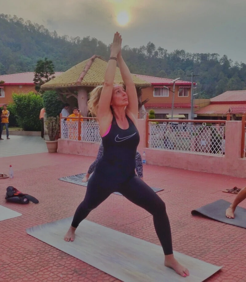 A practitioner in an upward salute at sunrise on the ashram terrace