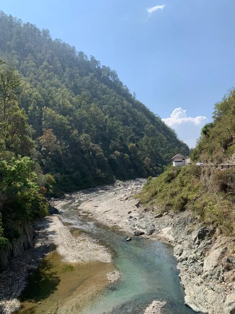 A clear Himalayan river running through the forested valley below the ashram